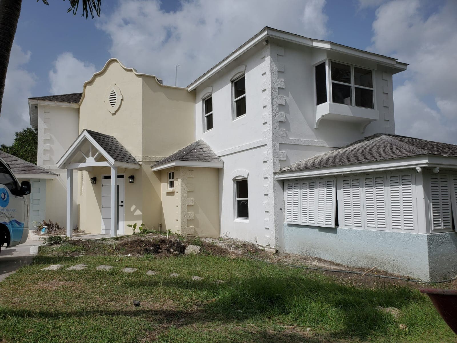 Cream-rendered residence exterior with blue metal roof, near completion