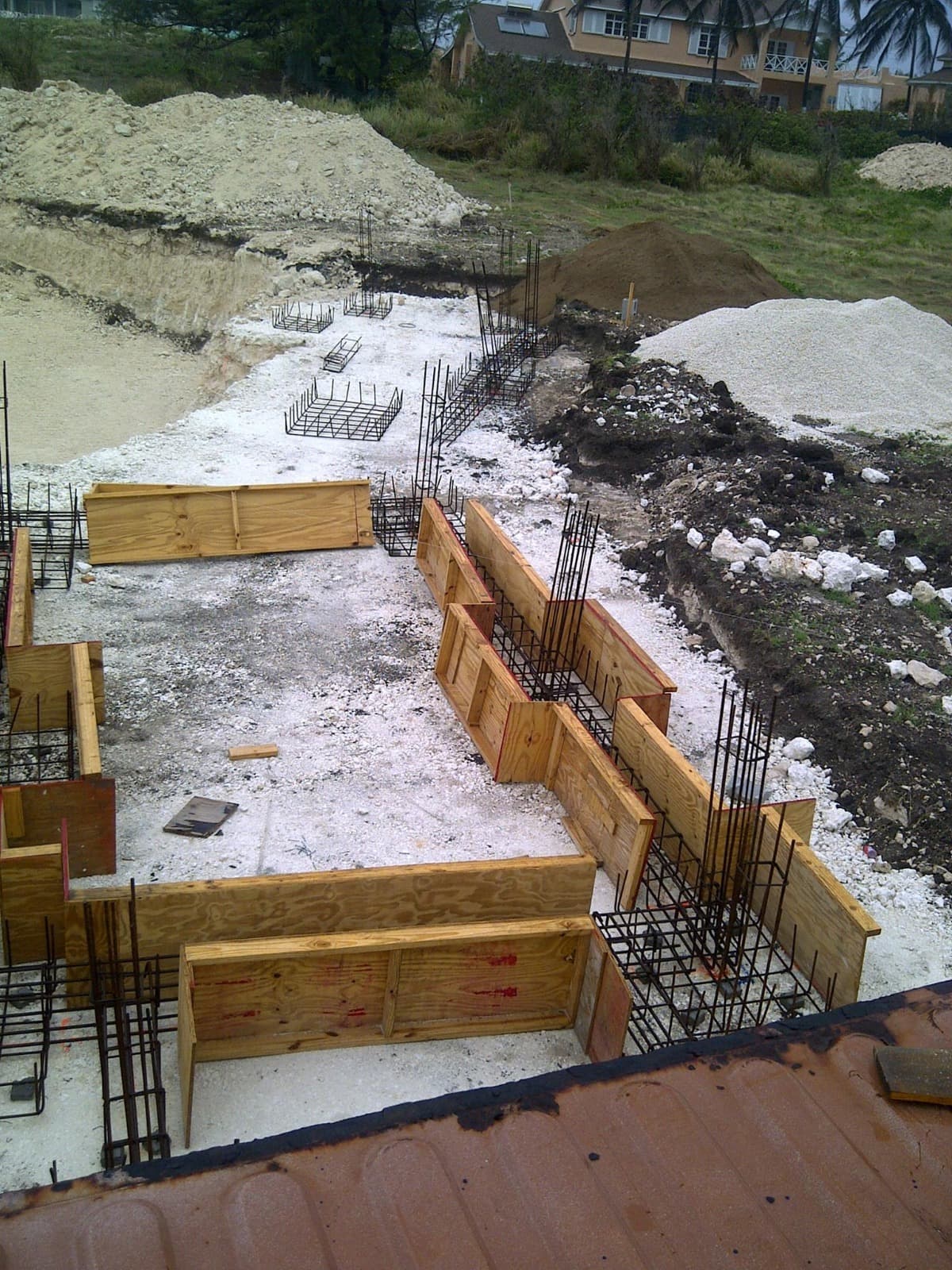 Elevated view of foundation formwork and rebar cages with residential neighbourhood in the background