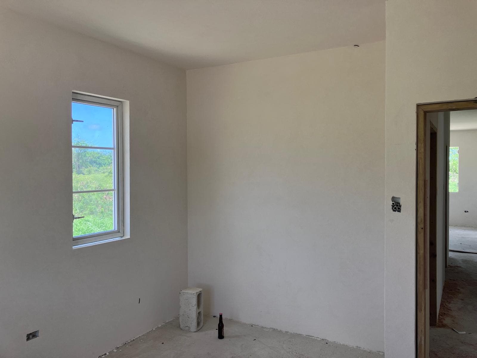 Plastered interior room awaiting finishes, single window