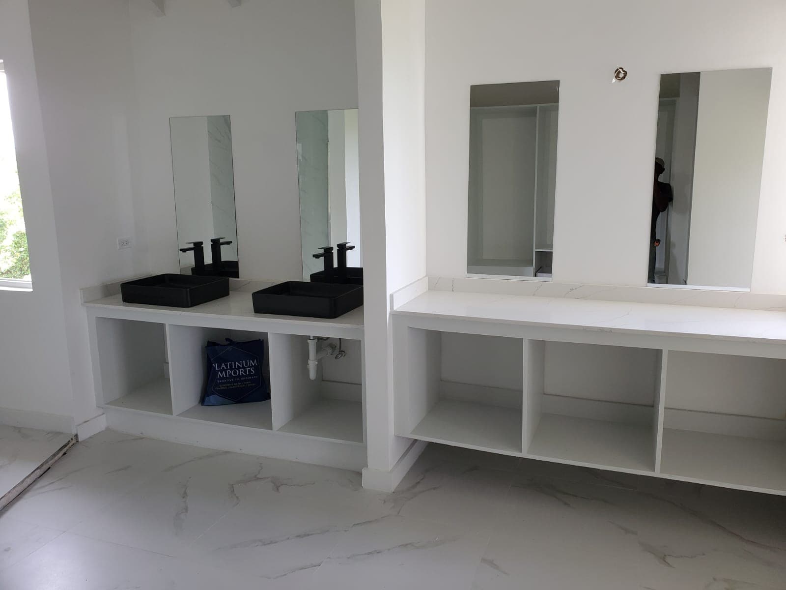 Double vanity bathroom with black vessel sinks and marble-tiled walls