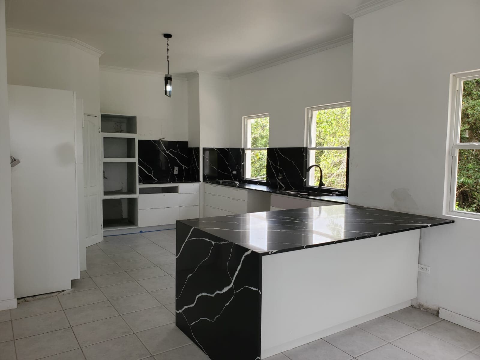 Kitchen with black marble countertops and open shelving mid-installation