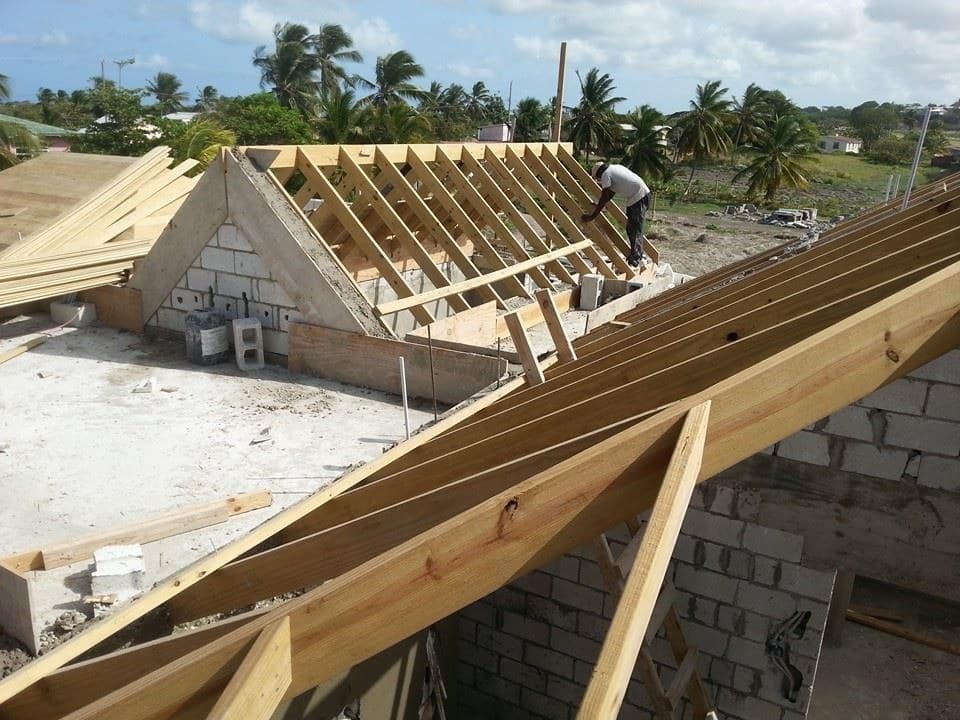 Timber roof truss framing under construction with a worker fixing framing at the ridge