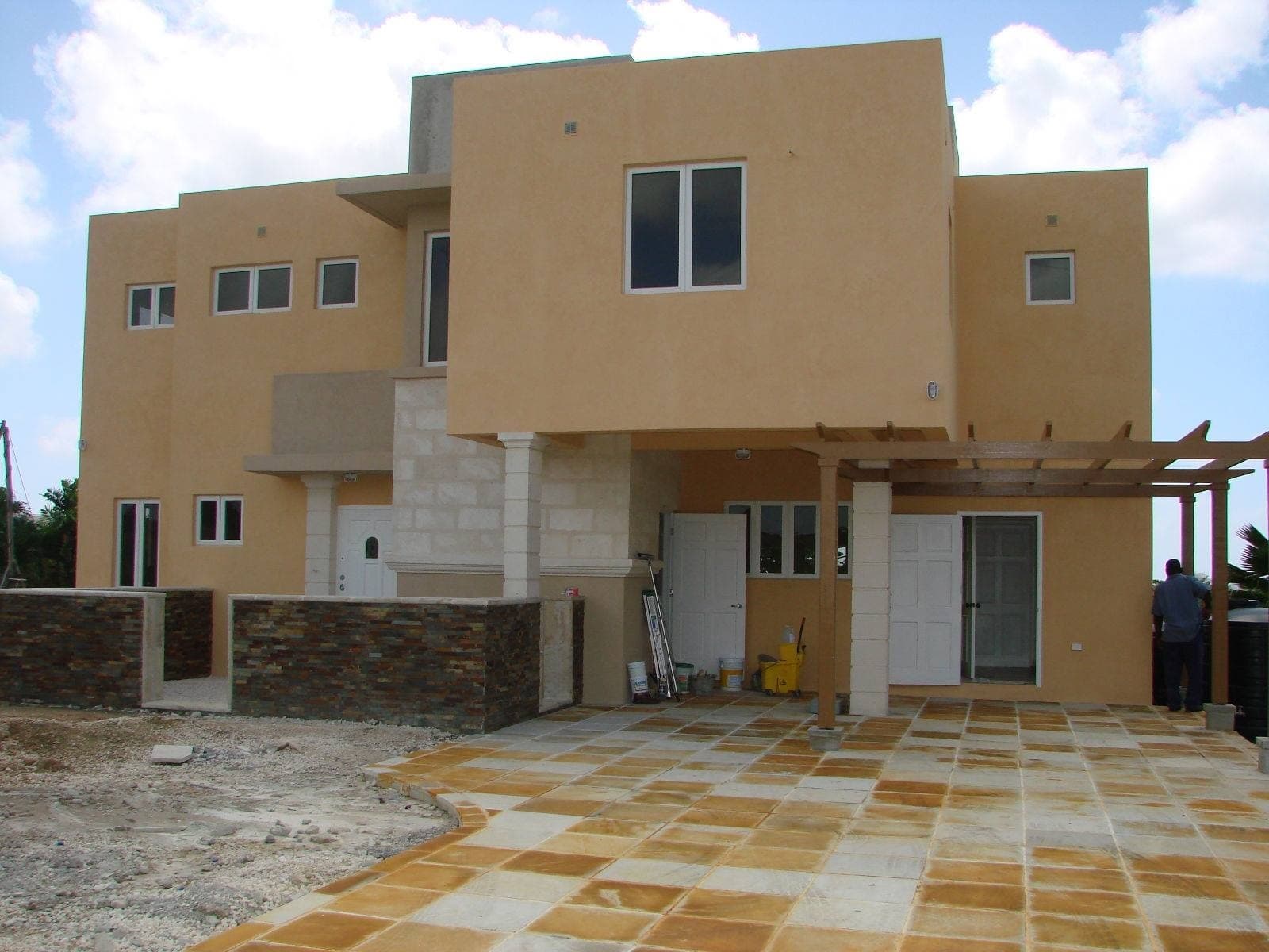 Orange stucco residence exterior with natural stone wall base and tiled patio