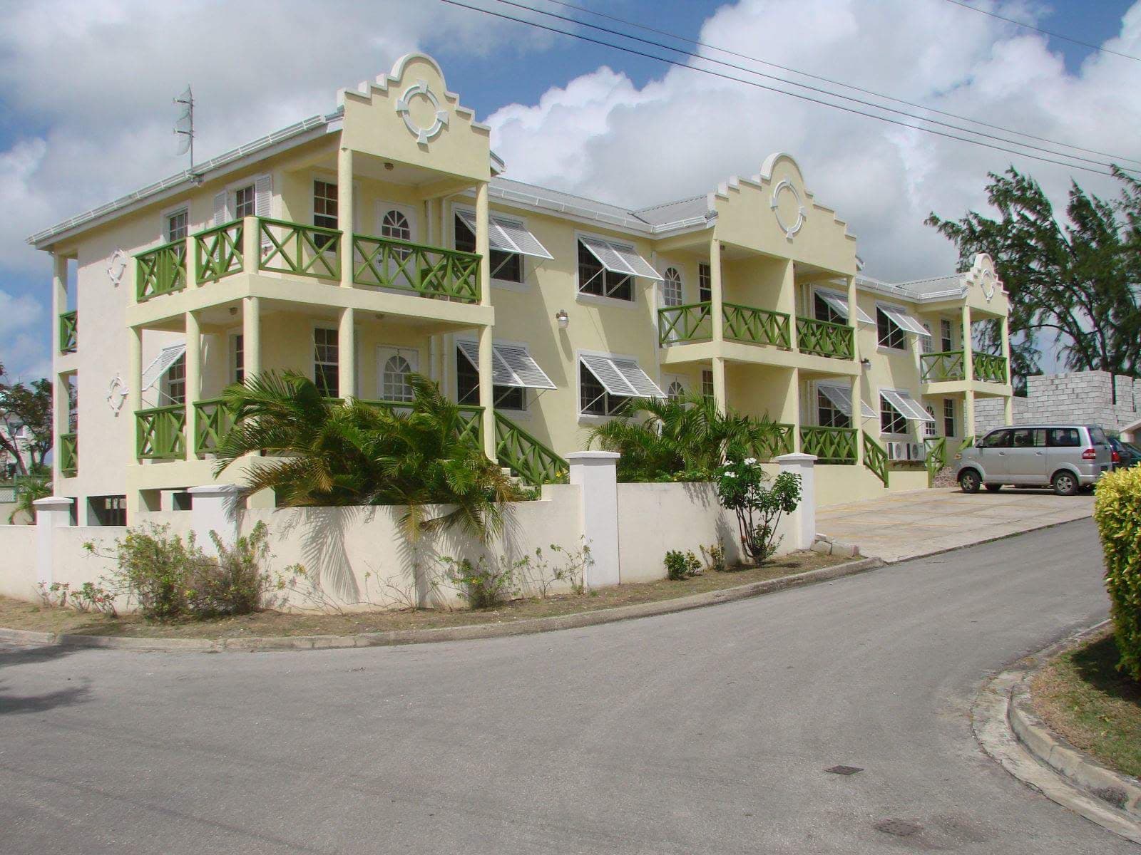 Multi-unit residential building in yellow and green with balconies and landscaping