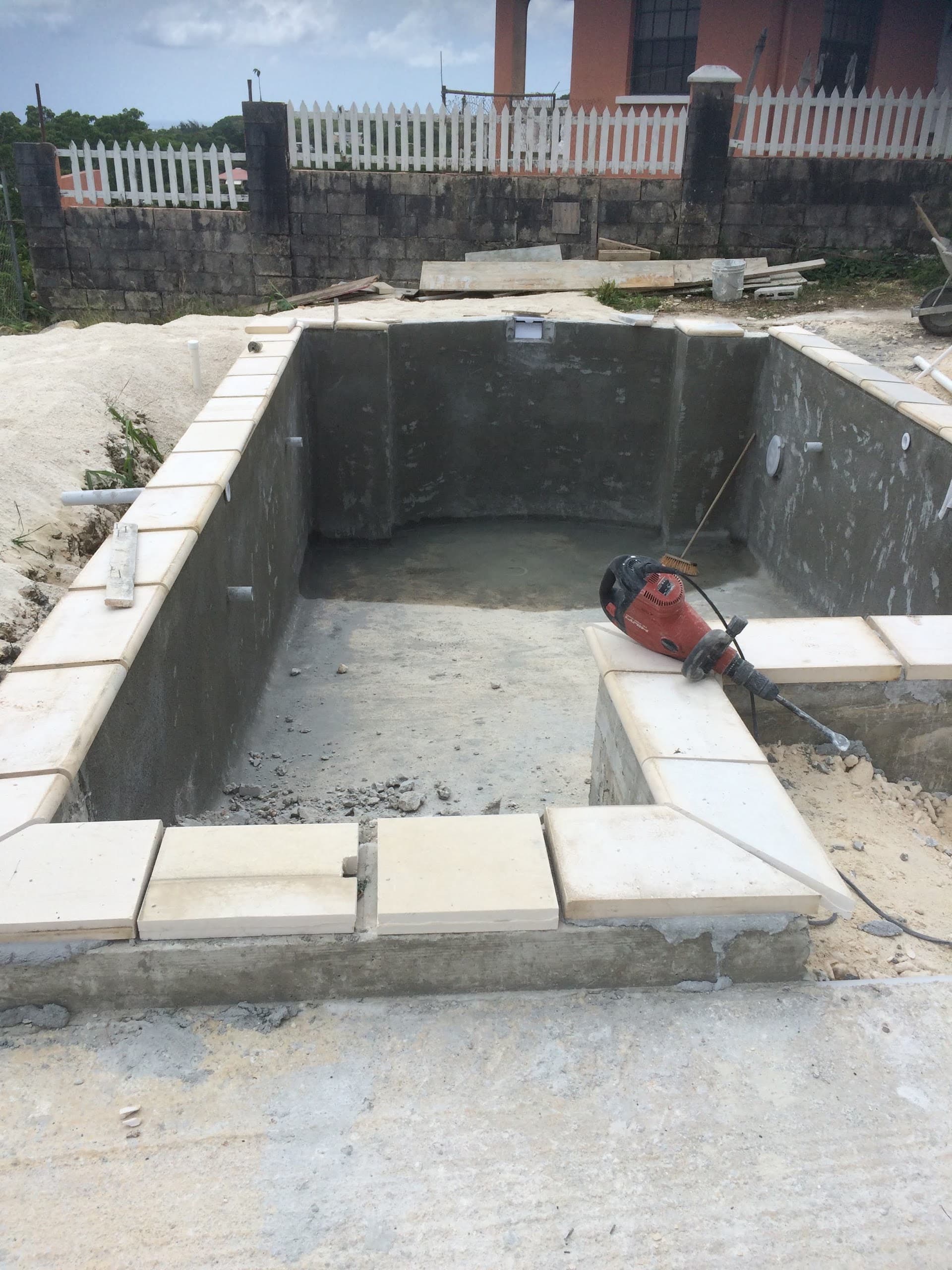 Concrete pool shell under construction with coping tiles being installed
