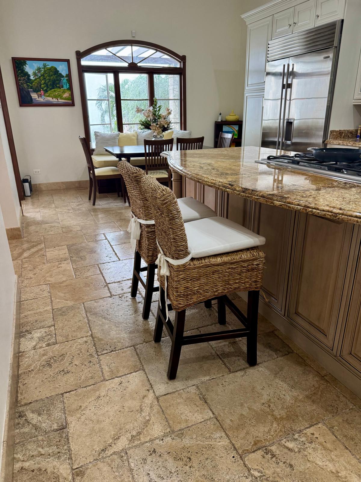 Completed kitchen with granite island, stainless appliances, and travertine flooring opening onto a breakfast nook