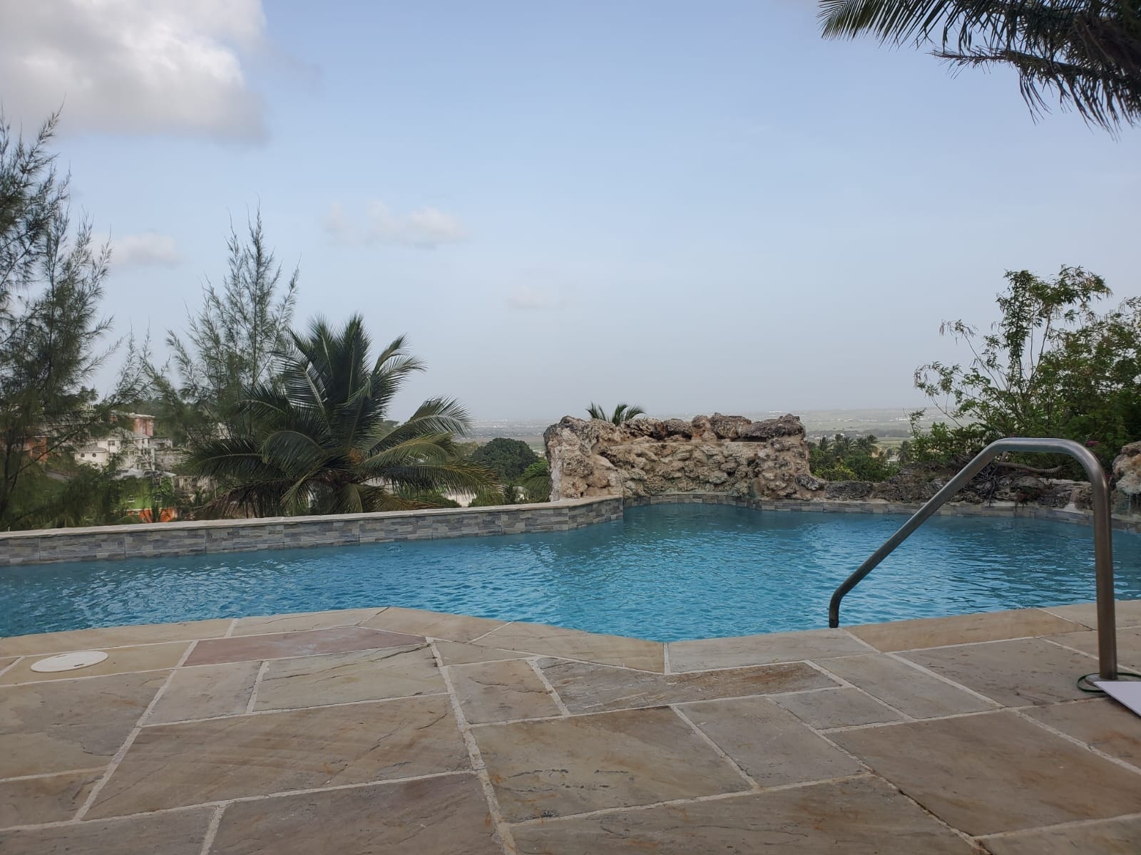 Pool with natural stone waterfall feature and hillside view over Barbados