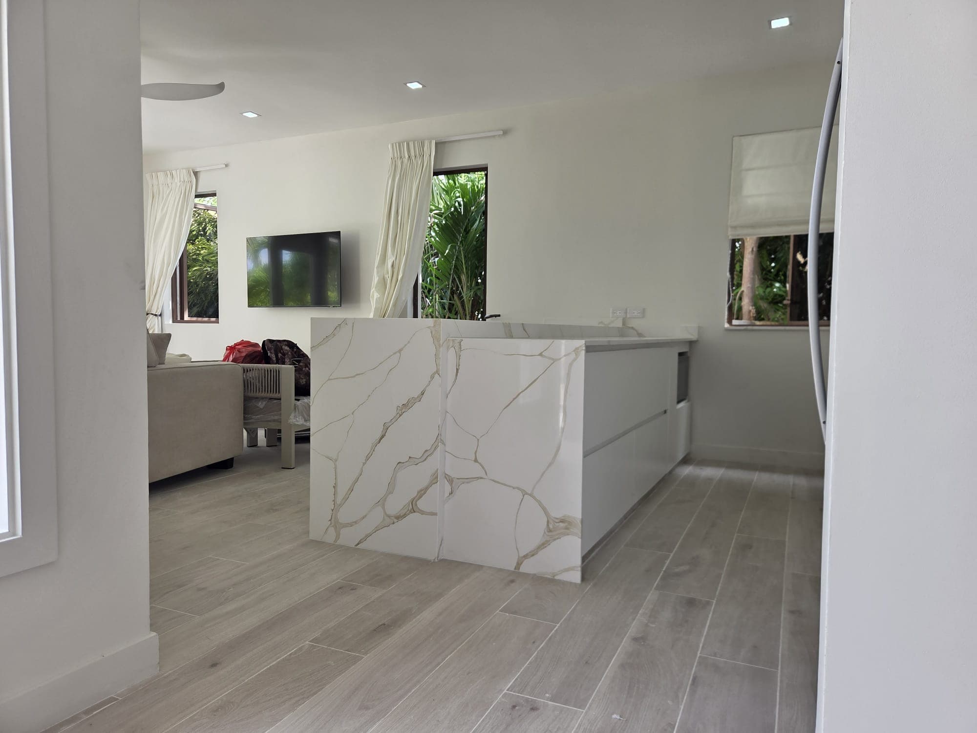 Kitchen with white marble waterfall-edge island and open-plan living area