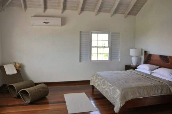 Bedroom with exposed timber vaulted ceiling and plantation shutters