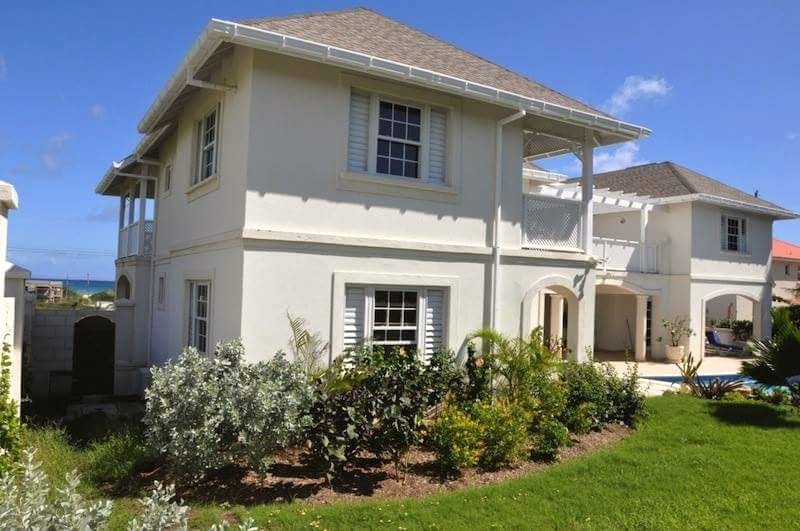 Completed coastal villa exterior with plantation shutters and pergola
