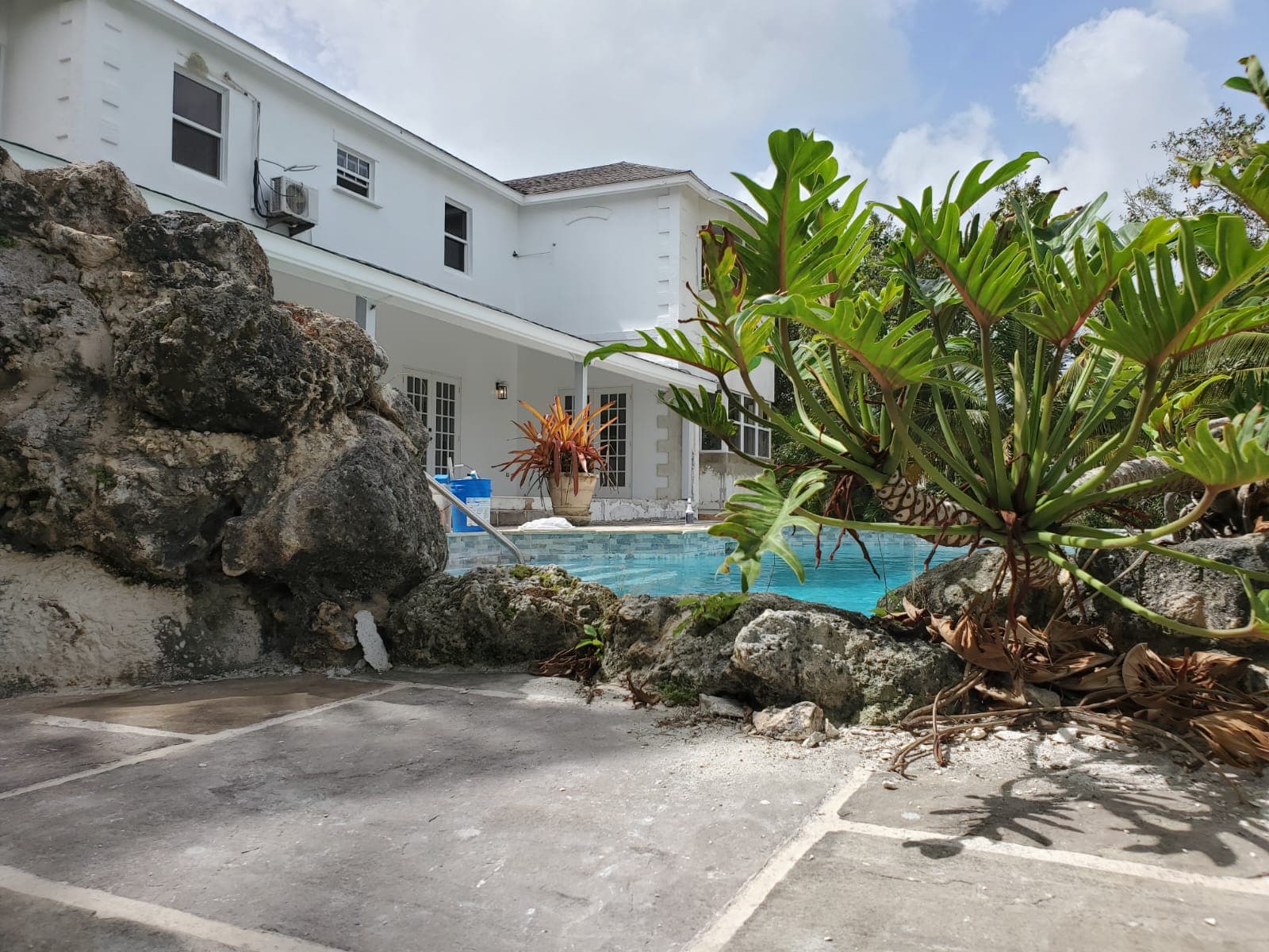 Pool terrace with natural rock feature at the rear of a residence undergoing renovation