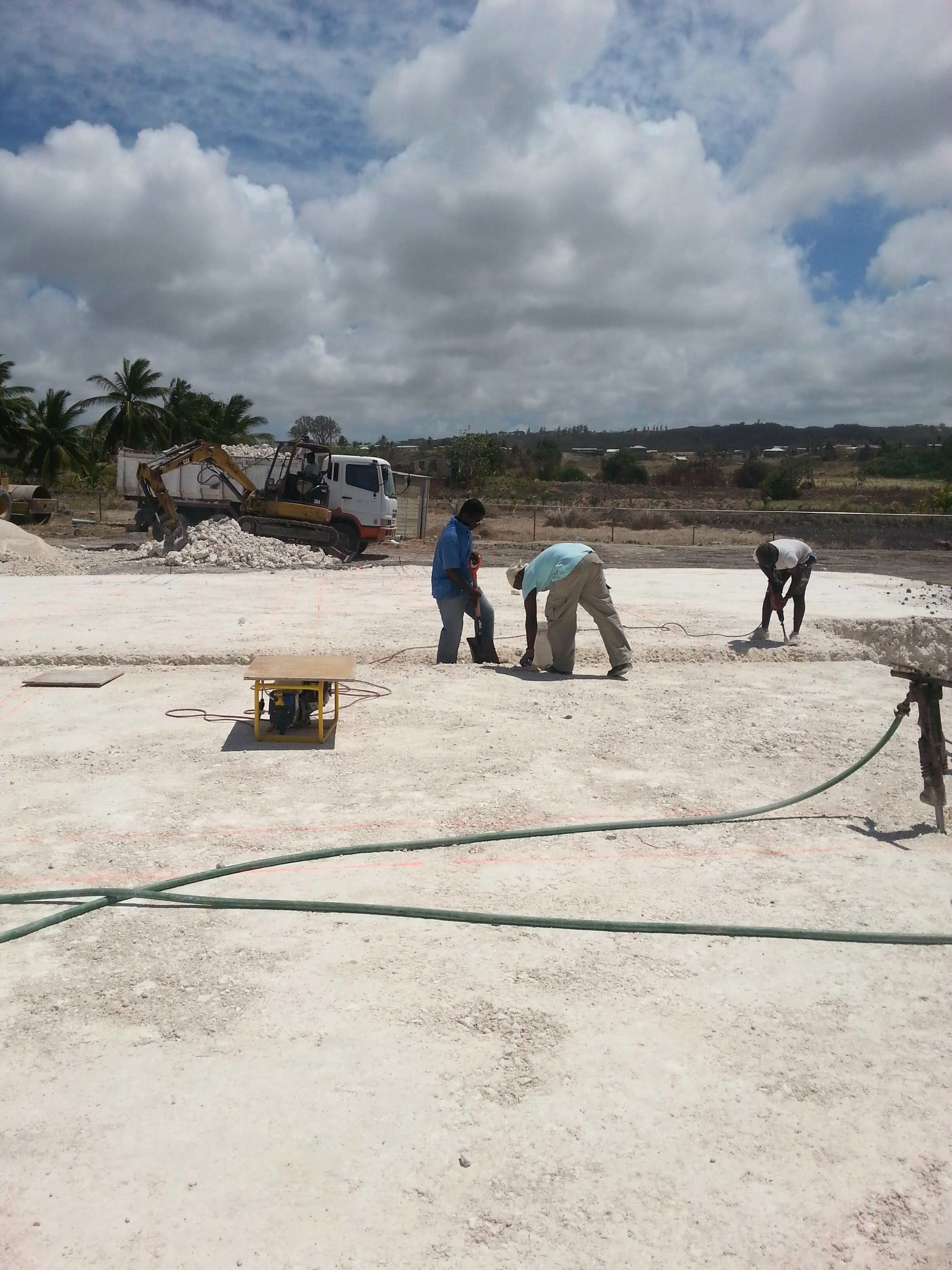 Workers preparing a concrete slab pour with excavation equipment on site