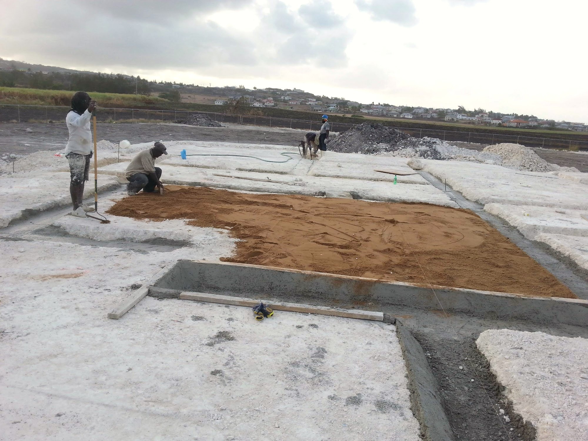 Workers finishing a concrete slab, aerial view of the surrounding site