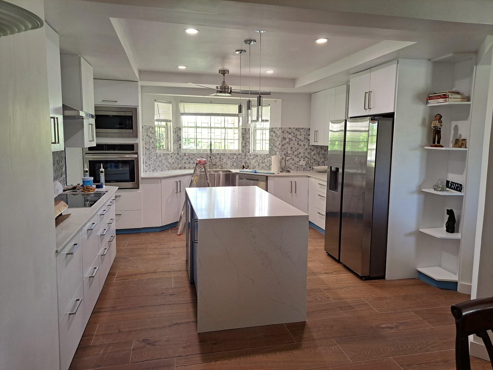 Renovated kitchen with white cabinetry, marble island, and dark wood flooring