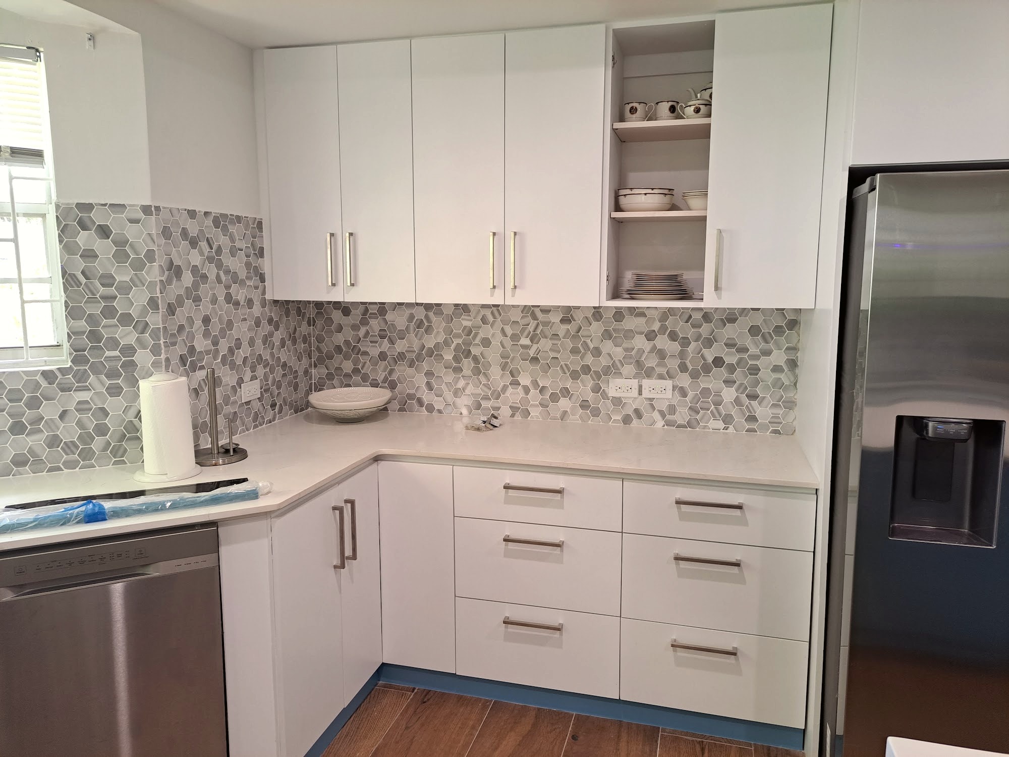 Second kitchen renovation with white cabinetry and mosaic tile backsplash, finishing works underway