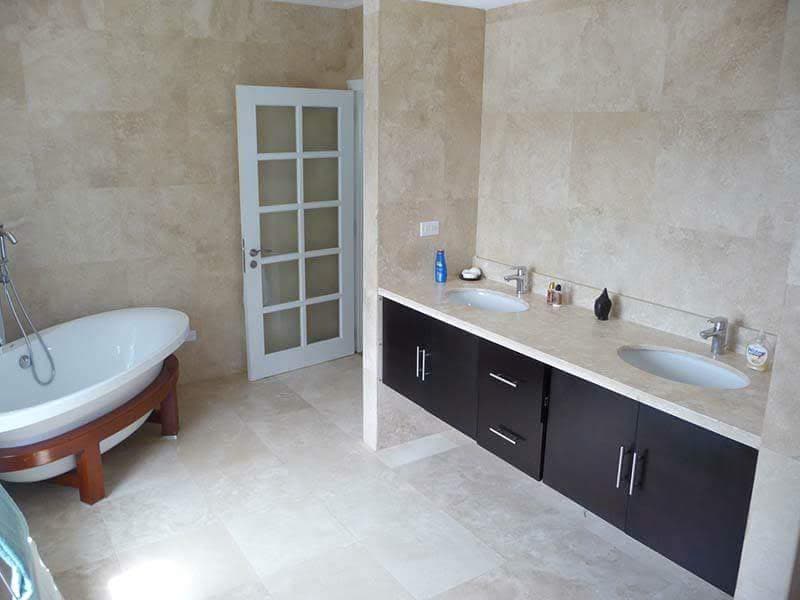Primary bathroom with freestanding tub and marble-tiled walls
