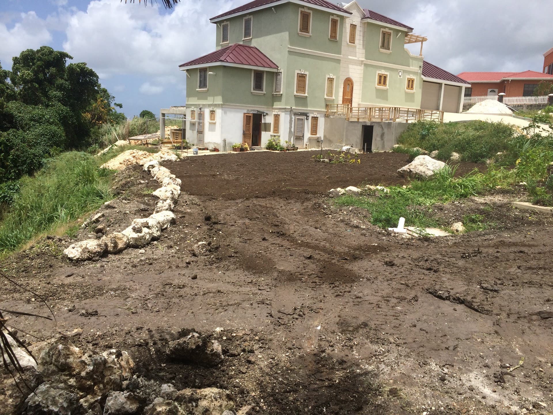 Skid-steer loader working the site with residence and neighbouring property in background